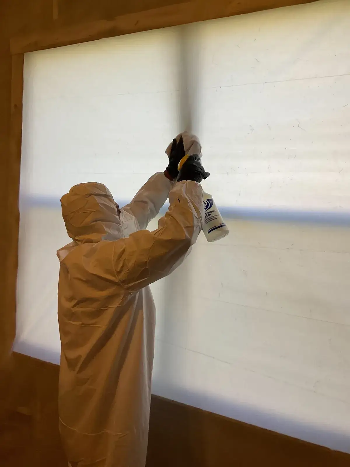 Technician performing mold remediation inside a contained work area.