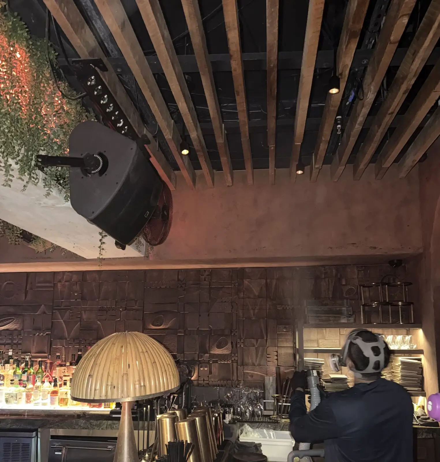 Technician in a full-face respirator fogging a restaurant bar and glassware storage in Miami Beach.