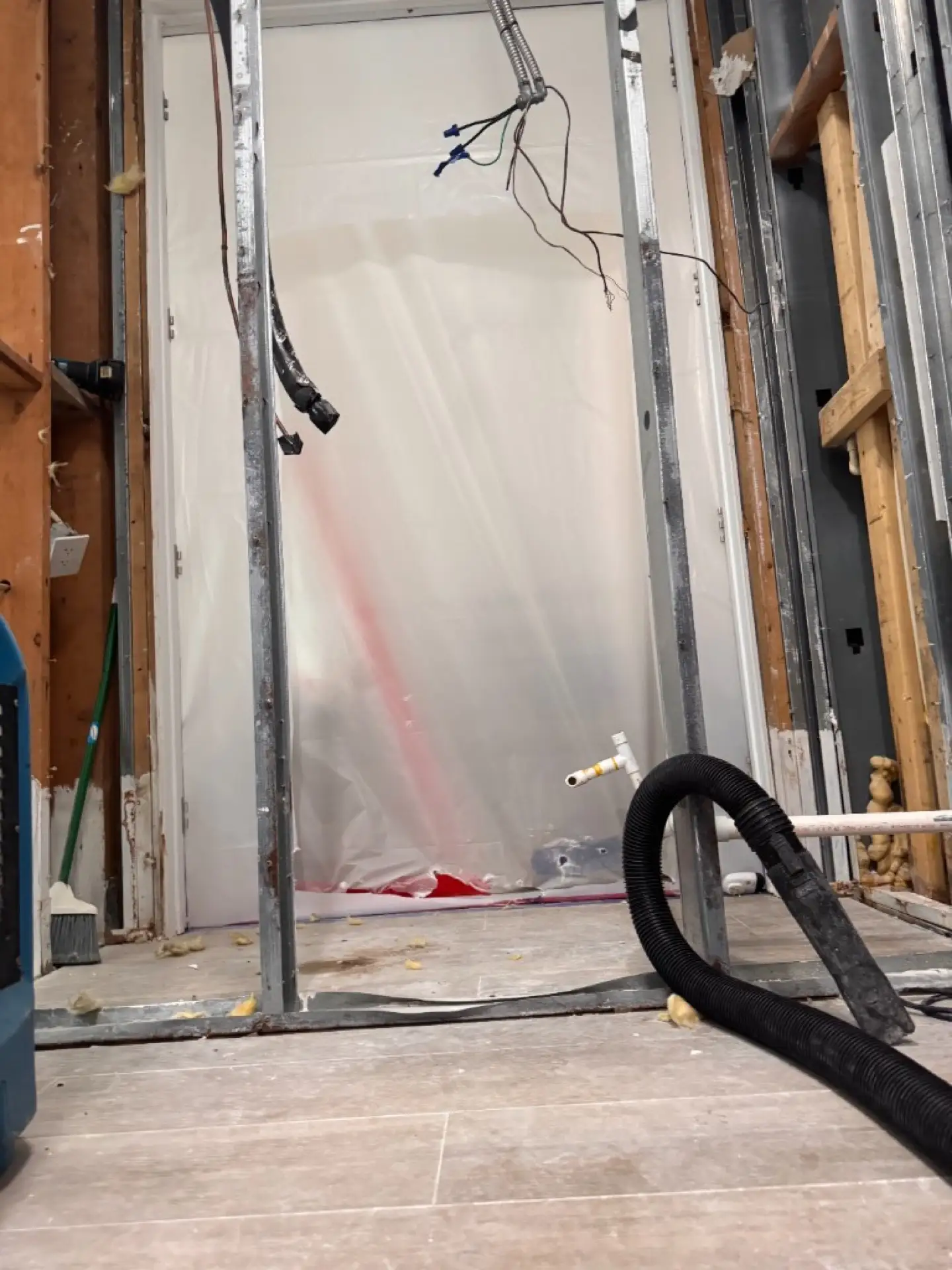 Sealed plastic barrier and exposed framing during controlled mold remediation in Davie
