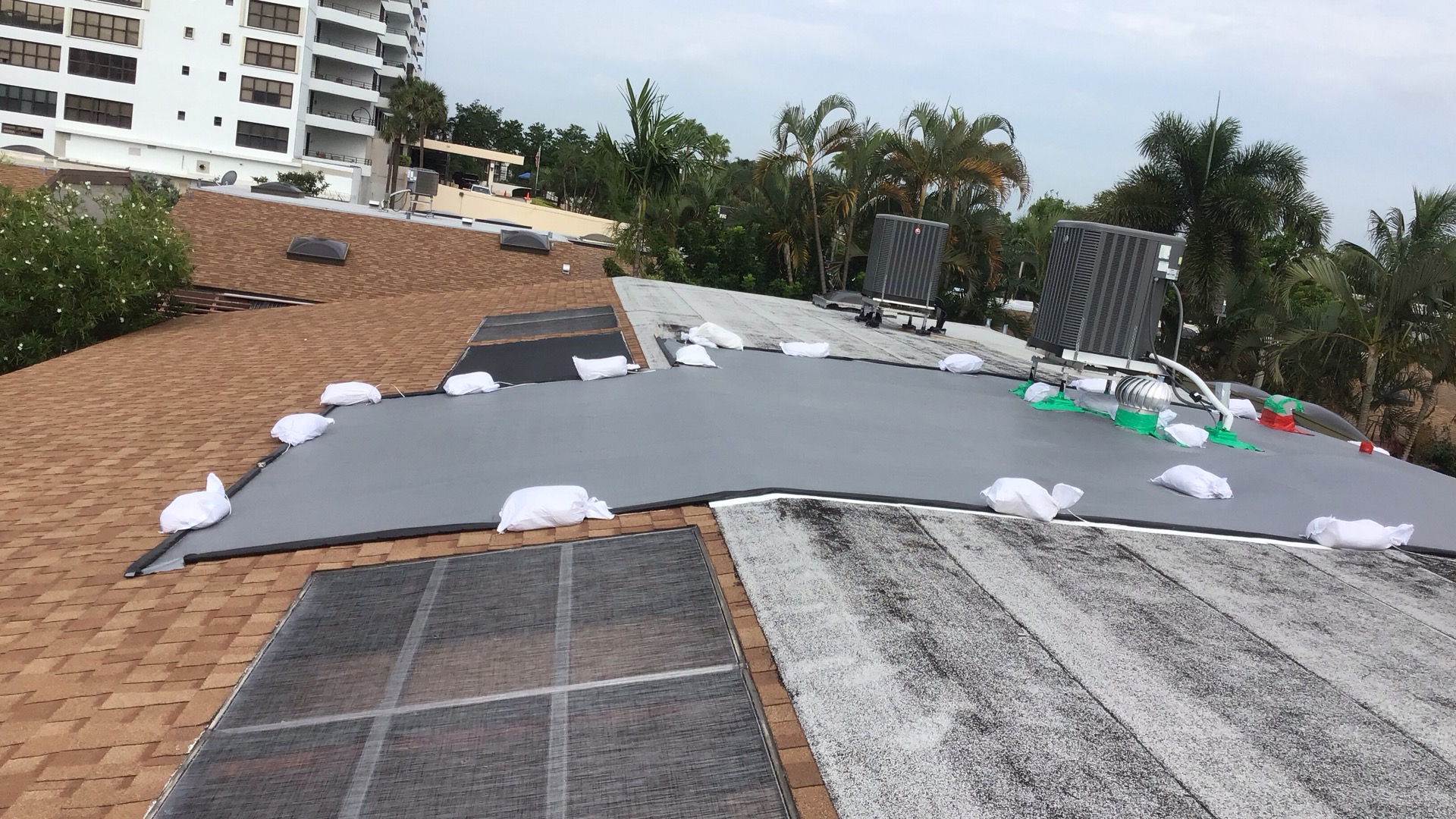 Commercial tarp installation in progress on pitched roof