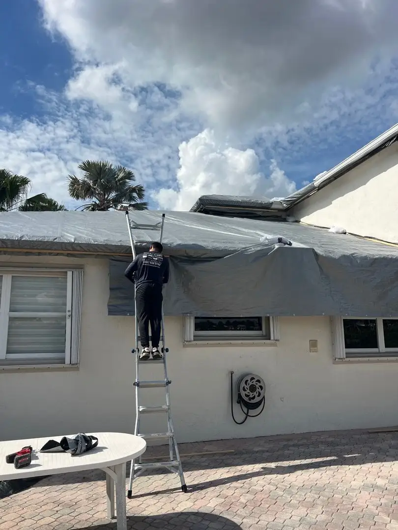Professional grey tarp installation on damaged Florida roof for emergency storm protection